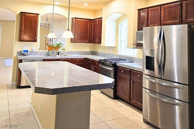 6339 Sharp Rock Ct, Las Vegas, NV 89139 - kitchen featuring appliances with stainless steel finishes, light tile patterned floors, a sink, arched walkways, and a center island