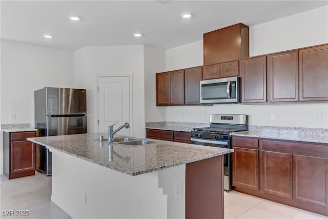 7256 Saxby Ave, Las Vegas, NV 89113 - kitchen featuring appliances with stainless steel finishes, a sink, light tile patterned flooring, light stone counters, and a kitchen island with sink