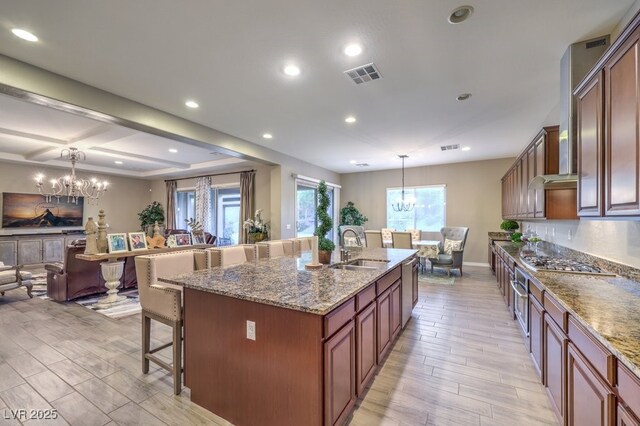 9760 Arch Canyon Ct, Las Vegas, NV 89149 - kitchen with a chandelier, a sink, a breakfast bar area, light wood finished floors, and open floor plan