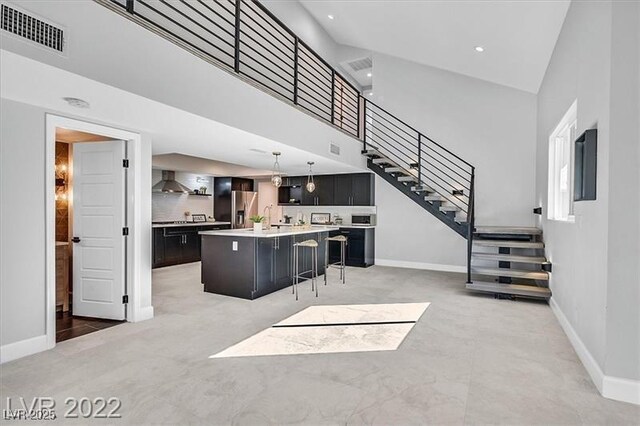 778 Vegas Valley Dr, Las Vegas, NV 89109 - kitchen with stainless steel fridge with ice dispenser, wall chimney range hood, baseboards, a breakfast bar area, and a center island