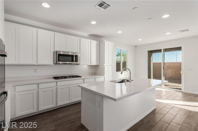10328 Apefly St, Las Vegas, NV 89141 - kitchen with stainless steel microwave, a sink, wood finish floors, gas stovetop, and white cabinetry