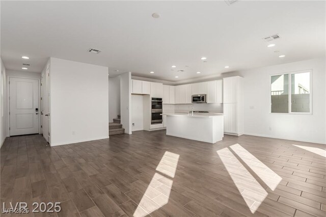 10328 Apefly St, Las Vegas, NV 89141 - unfurnished living room with wood finished floors, recessed lighting, stairs, baseboards, and a sink
