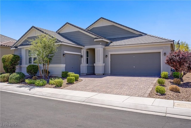 view of front of property featuring a garage, decorative driveway, and a tile roof