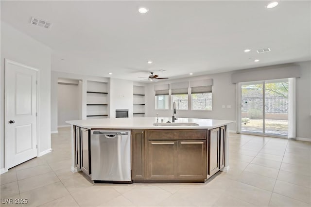 kitchen featuring stainless steel dishwasher, a sink, light countertops, ceiling fan, and an island with sink
