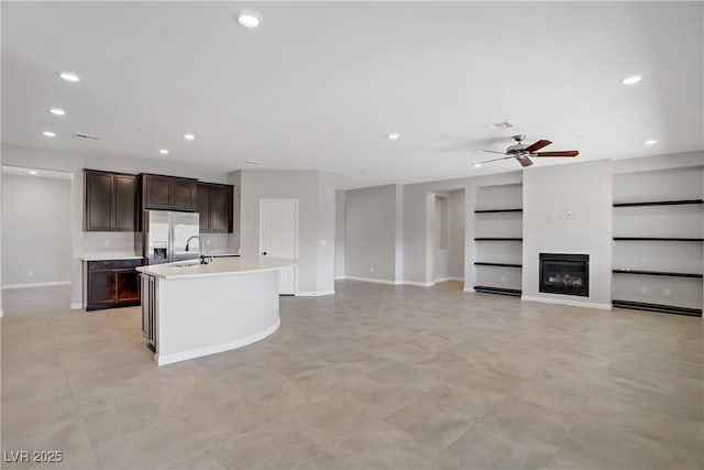 kitchen featuring fridge with ice dispenser, light countertops, a ceiling fan, a sink, and dark brown cabinetry