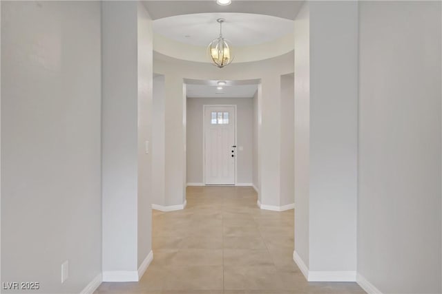corridor with a chandelier, baseboards, and light tile patterned floors