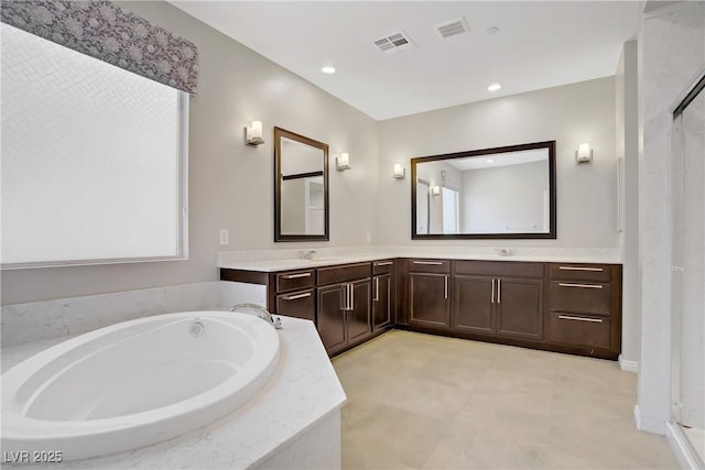 bathroom featuring a garden tub, double vanity, and recessed lighting