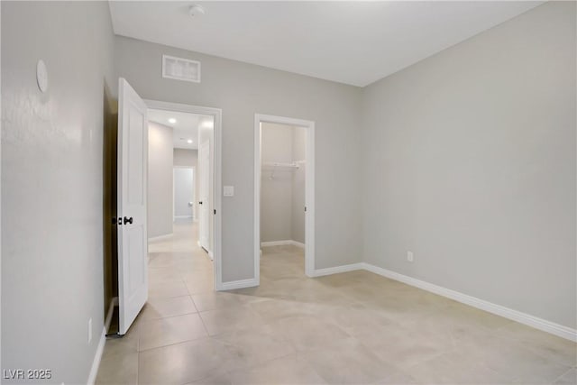 unfurnished bedroom featuring a spacious closet, light tile patterned floors, baseboards, a closet, and recessed lighting