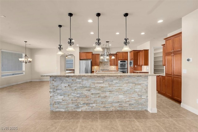 7668 Friendly Breeze Ct, Las Vegas, NV 89123 - kitchen with appliances with stainless steel finishes, brown cabinetry, recessed lighting, a chandelier, and baseboards