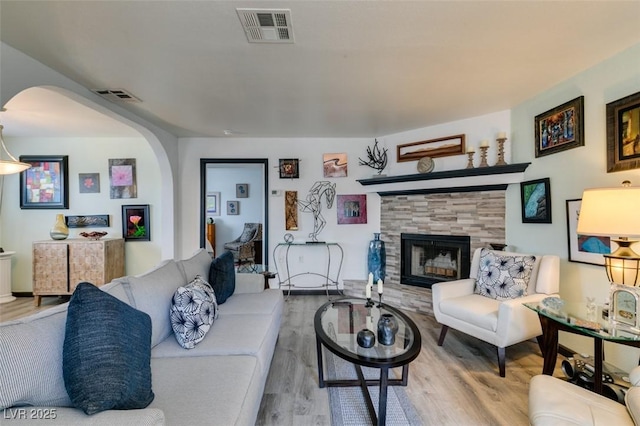 living room featuring arched walkways, wood finished floors, and a tile fireplace