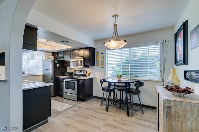 kitchen featuring appliances with stainless steel finishes, light wood finished floors, plenty of natural light, and arched walkways