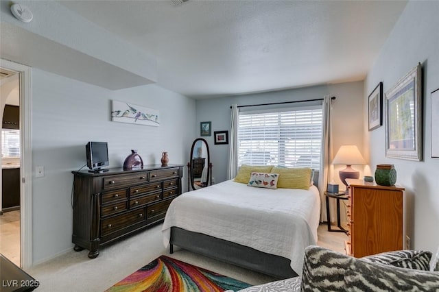 bedroom with multiple windows, light carpet, arched walkways, and baseboards