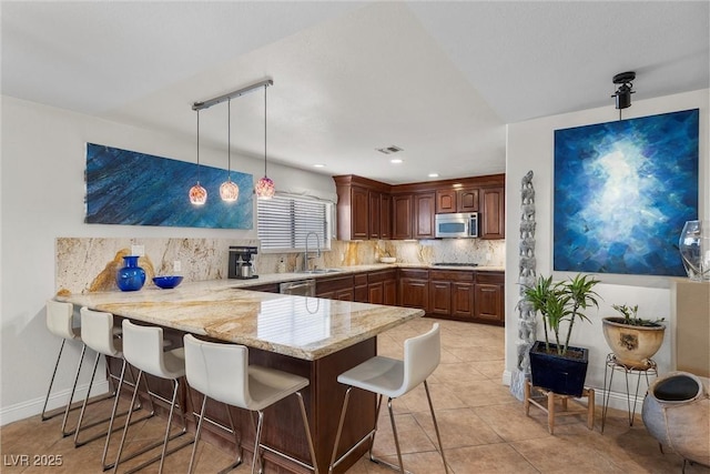 4185 W Arby Ave, Las Vegas, NV 89118 - kitchen with a peninsula, stainless steel microwave, tasteful backsplash, a kitchen breakfast bar, and light stone counters