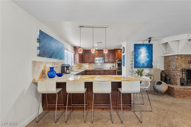 4185 W Arby Ave, Las Vegas, NV 89118 - kitchen with stainless steel appliances, a peninsula, light stone countertops, and a kitchen bar