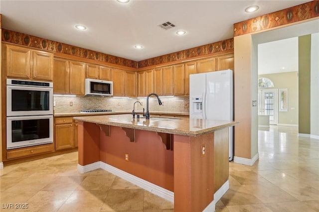 395 Suzanne Peak Ct, Henderson, NV 89012 - kitchen with white double oven, stainless steel microwave, gas cooktop, light tile patterned floors, and light stone countertops