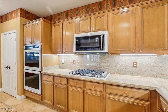 395 Suzanne Peak Ct, Henderson, NV 89012 - kitchen with stainless steel appliances, tasteful backsplash, light tile patterned floors, and light stone countertops