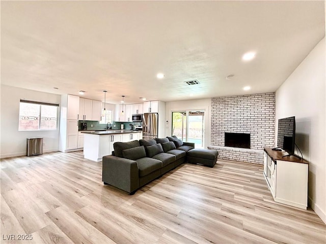 4881 E Imperial Ave, Las Vegas, NV 89104 - living area featuring a brick fireplace, recessed lighting, light wood-style flooring, and baseboards