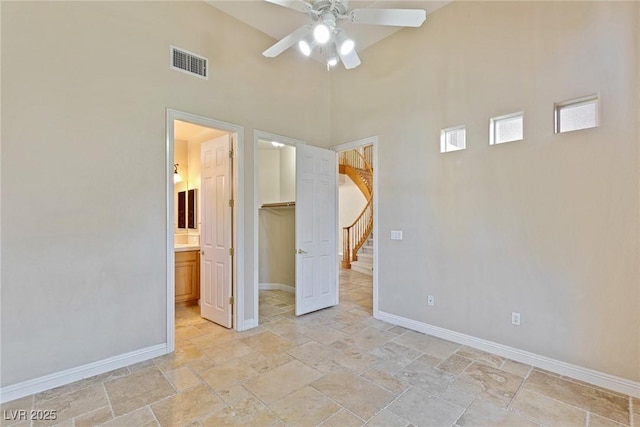 10761 Capesthorne Way, Las Vegas, NV 89135 - unfurnished bedroom featuring a walk in closet, stone tile flooring, baseboards, a towering ceiling, and a closet