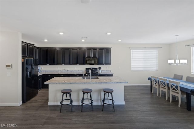 4050 Midnight Crest Ave, North Las Vegas, NV 89031 - kitchen with black appliances, a sink, baseboards, a breakfast bar, and a center island with sink