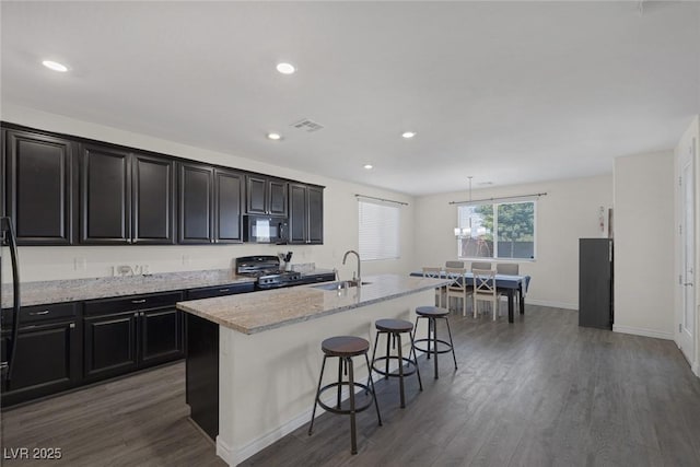 4050 Midnight Crest Ave, North Las Vegas, NV 89031 - kitchen featuring black microwave, gas range, a sink, wood finished floors, and a kitchen breakfast bar