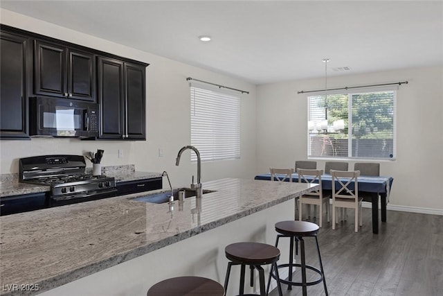 4050 Midnight Crest Ave, North Las Vegas, NV 89031 - kitchen featuring black appliances, a sink, a kitchen breakfast bar, light wood-style flooring, and light stone counters