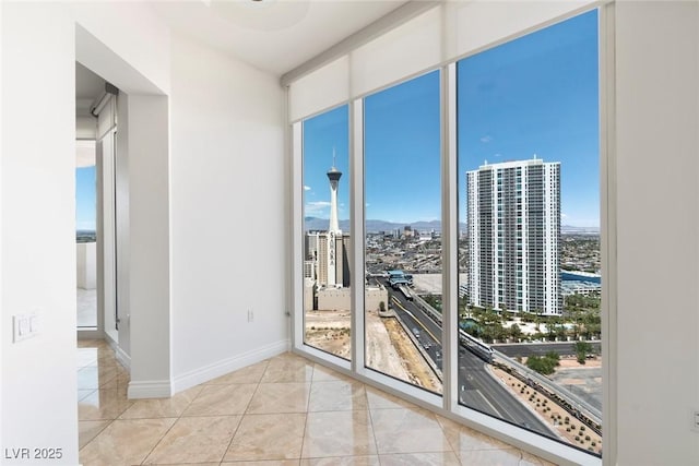 spare room featuring a view of city, tile patterned flooring, a mountain view, and baseboards