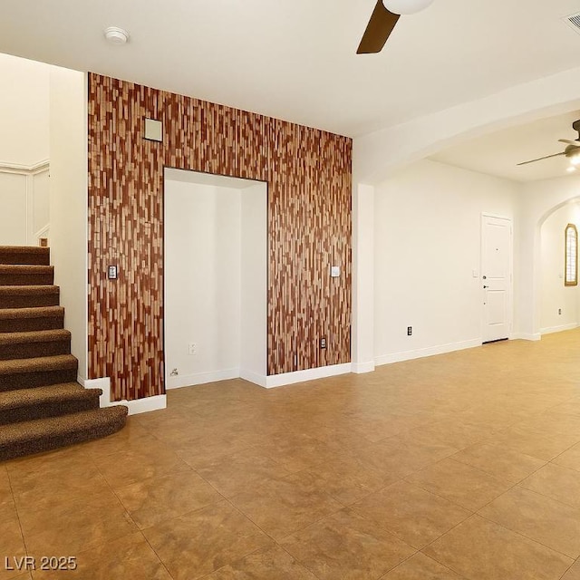 5380 Flowing Spring St, Las Vegas, NV 89122 - empty room featuring ceiling fan, arched walkways, an accent wall, a smoke detector, and stairway