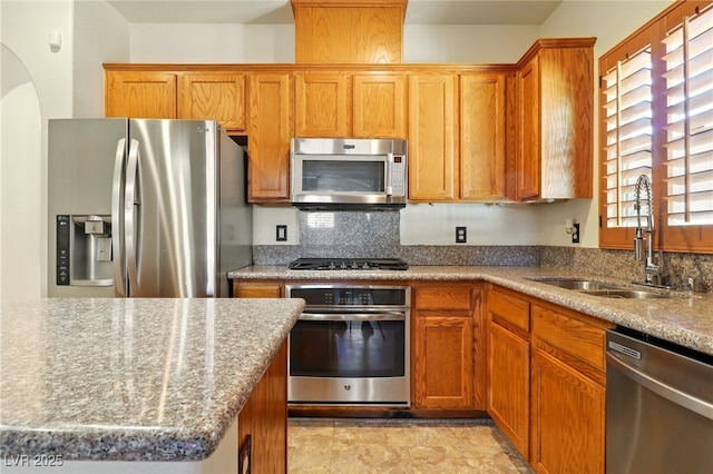 5380 Flowing Spring St, Las Vegas, NV 89122 - kitchen featuring appliances with stainless steel finishes, backsplash, light stone countertops, and arched walkways