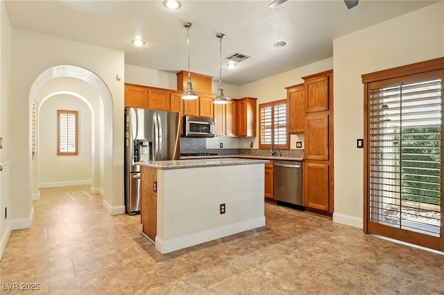 5380 Flowing Spring St, Las Vegas, NV 89122 - kitchen featuring appliances with stainless steel finishes, a center island, brown cabinets, decorative light fixtures, and recessed lighting