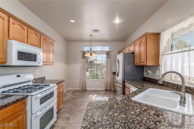 8266 Lincoln Valley St, Las Vegas, NV 89123 - kitchen with white appliances, a sink, a chandelier, dark stone countertops, and pendant lighting
