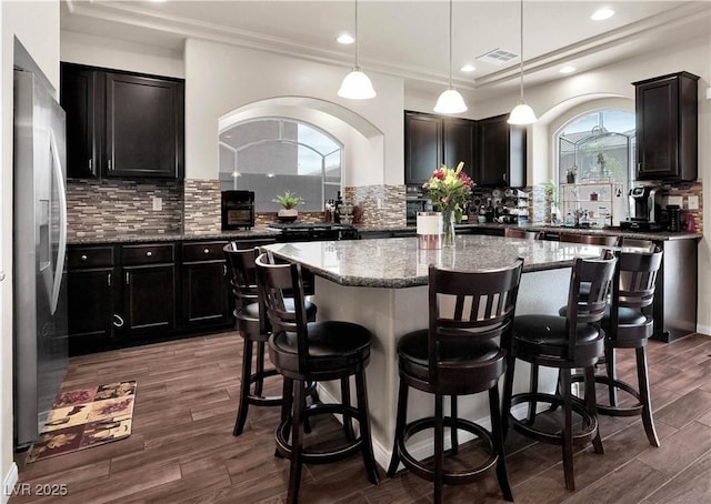 6465 Grande River Ct, Las Vegas, NV 89139 - kitchen with stainless steel fridge, a center island, stone counters, decorative backsplash, and recessed lighting
