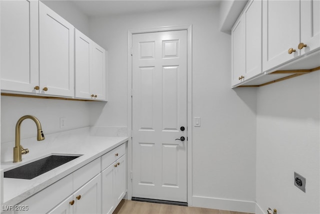 washroom featuring cabinet space, hookup for an electric dryer, light wood-type flooring, and baseboards