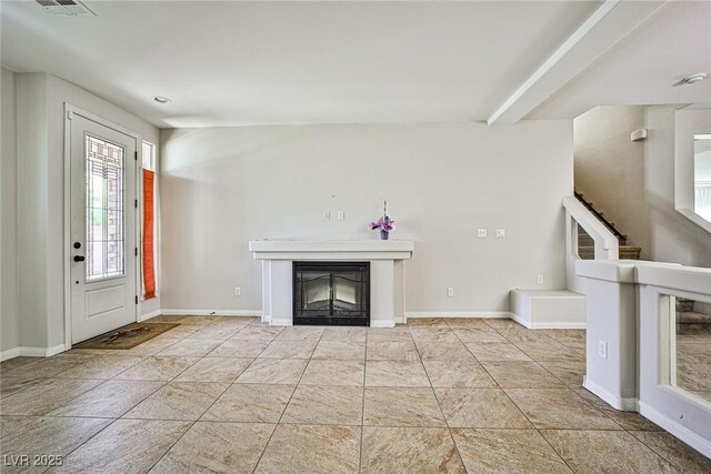 6409 Shawnee Springs Ct, Las Vegas, NV 89139 - unfurnished living room featuring a glass covered fireplace, baseboards, and stairway