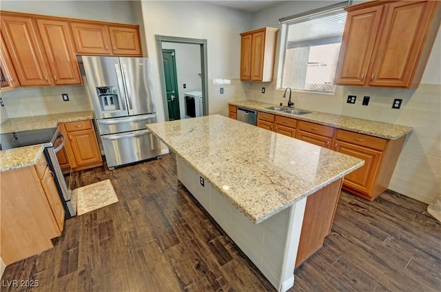 3938 E Chaffe Ave, Pahrump, NV 89061 - kitchen with appliances with stainless steel finishes, a sink, washer / clothes dryer, dark wood-type flooring, and light stone counters