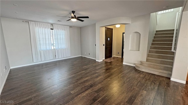3938 E Chaffe Ave, Pahrump, NV 89061 - unfurnished living room featuring ceiling fan, dark wood-type flooring, stairs, arched walkways, and baseboards