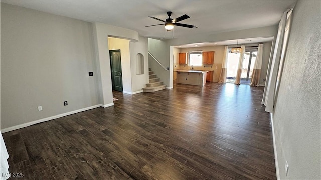 3938 E Chaffe Ave, Pahrump, NV 89061 - unfurnished living room featuring a ceiling fan, dark wood-type flooring, baseboards, and stairs
