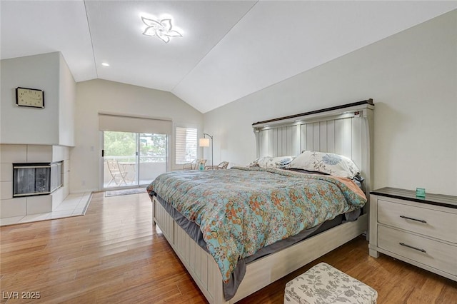 8591 Heather Downs Dr, Las Vegas, NV 89113 - bedroom featuring vaulted ceiling, access to exterior, light wood-type flooring, and a tiled fireplace