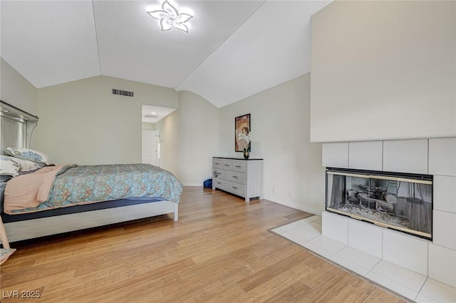 8591 Heather Downs Dr, Las Vegas, NV 89113 - bedroom featuring a tiled fireplace, vaulted ceiling, light wood finished floors, and baseboards