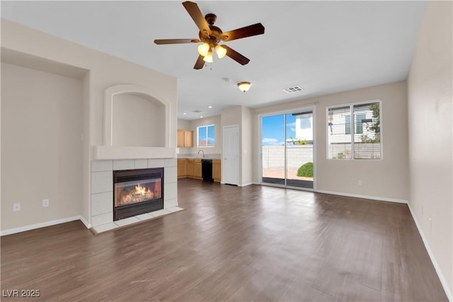 82 Autumn Day St, Henderson, NV 89012 - unfurnished living room with healthy amount of natural light, dark wood-style flooring, a tile fireplace, and ceiling fan