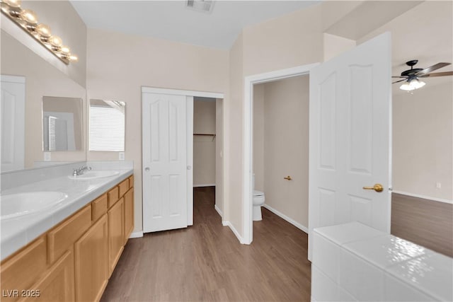 82 Autumn Day St, Henderson, NV 89012 - bathroom with toilet, wood finished floors, a ceiling fan, double vanity, and baseboards