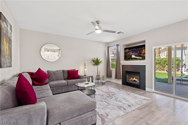 191 Reed Ln, Henderson, NV 89074 - living room with wood finished floors, a ceiling fan, a warm lit fireplace, and baseboards