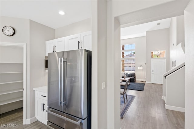 191 Reed Ln, Henderson, NV 89074 - kitchen with freestanding refrigerator, white cabinetry, light wood-type flooring, and baseboards