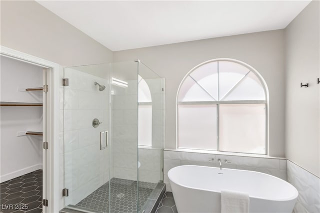 191 Reed Ln, Henderson, NV 89074 - bathroom featuring a soaking tub, a stall shower, tile patterned flooring, a spacious closet, and tile walls