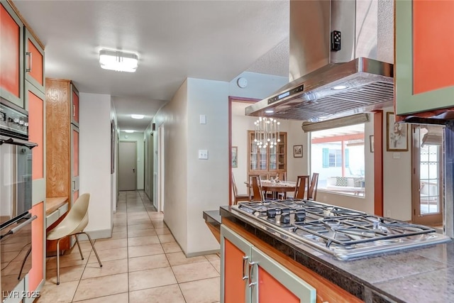 1721 E Oakey Blvd, Las Vegas, NV 89104 - kitchen with ventilation hood, appliances with stainless steel finishes, light tile patterned flooring, baseboards, and a chandelier