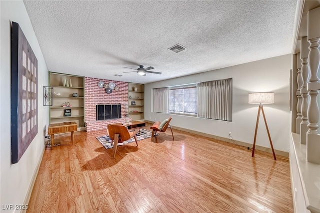 1721 E Oakey Blvd, Las Vegas, NV 89104 - living area with a ceiling fan, a textured ceiling, wood finished floors, baseboards, and a fireplace