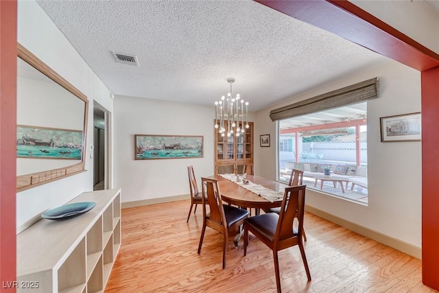 1721 E Oakey Blvd, Las Vegas, NV 89104 - dining space featuring light wood-style flooring, a textured ceiling, a chandelier, and baseboards
