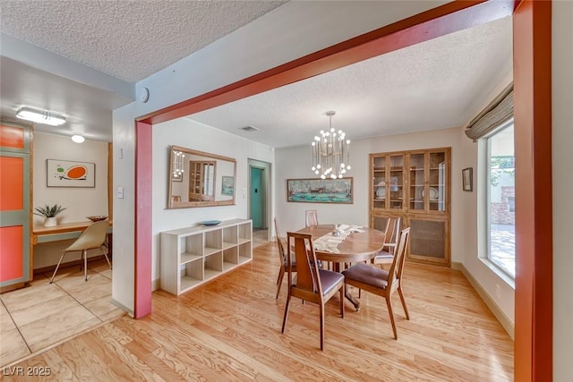 1721 E Oakey Blvd, Las Vegas, NV 89104 - dining space with a textured ceiling, light wood finished floors, a chandelier, and baseboards