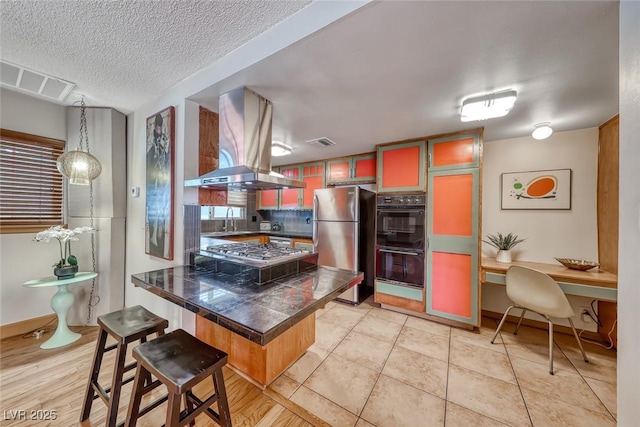 1721 E Oakey Blvd, Las Vegas, NV 89104 - kitchen featuring island exhaust hood, stainless steel appliances, a peninsula, a kitchen breakfast bar, and a sink