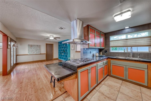 1721 E Oakey Blvd, Las Vegas, NV 89104 - kitchen featuring island range hood, dark countertops, stainless steel gas cooktop, a sink, and ceiling fan