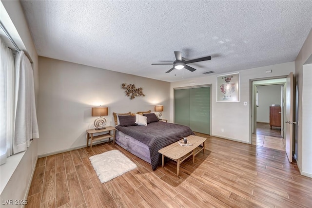1721 E Oakey Blvd, Las Vegas, NV 89104 - bedroom with a textured ceiling, light wood-type flooring, a closet, ceiling fan, and baseboards